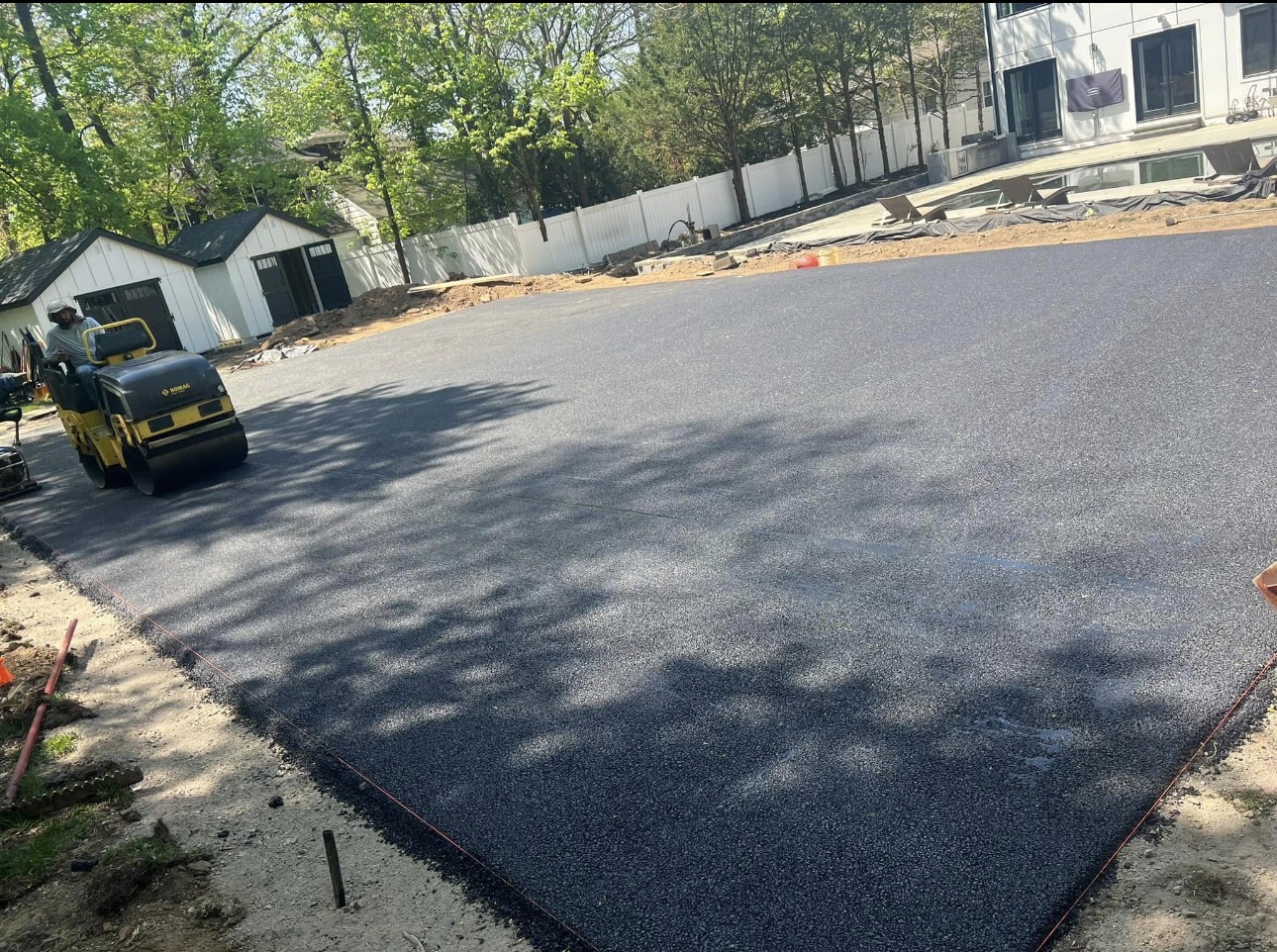 Fresh asphalt parking pad compacted with a roller in New Jersey