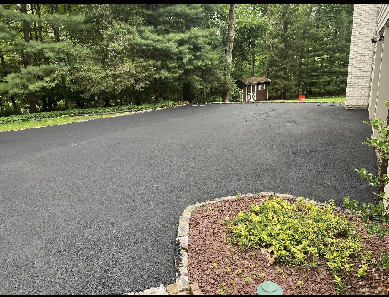 Wide smooth residential asphalt driveway with fresh landscaping